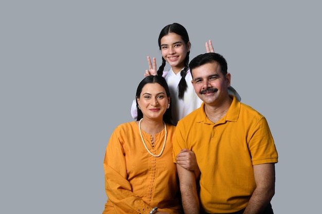 Hermosa y feliz familia joven sonriente contra la pared gris modelo paquistaní indio
