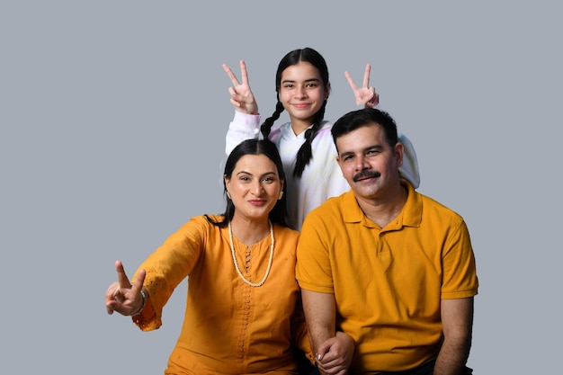 Hermosa y feliz familia joven sonriente contra la pared gris modelo paquistaní indio