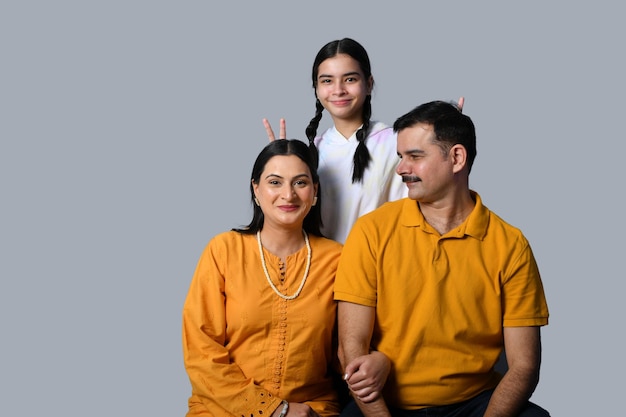 Hermosa y feliz familia joven sonriente contra la pared gris modelo paquistaní indio