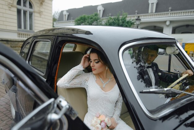 Hermosa feliz joven novia y el novio mirando desde retro auto