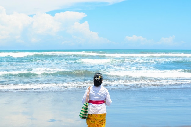 Hermosa y feliz mujer balinesa indonesia de mediana edad vestida de ceremonia tradicional en una playa tropical