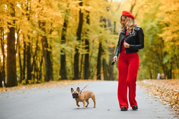 Hermosa y feliz mujer disfrutando en el parque caminando con su adorable bulldog francés