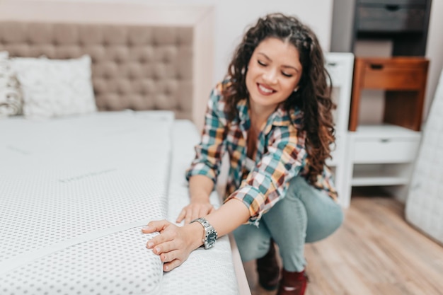 Hermosa y feliz mujer de mediana edad eligiendo nueva cama y colchón en una gran tienda de muebles