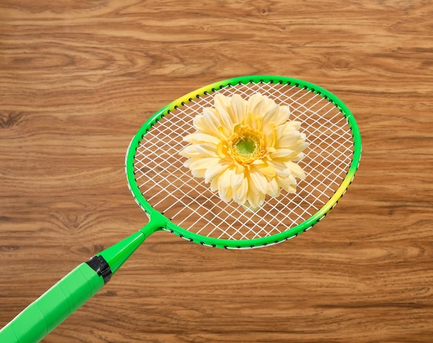 Una hermosa flor amarilla yace en una raqueta de bádminton concepto de juego deportivo y ocio