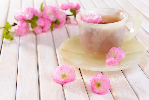 Hermosa flor de fruta con una taza de té en el primer plano de la mesa