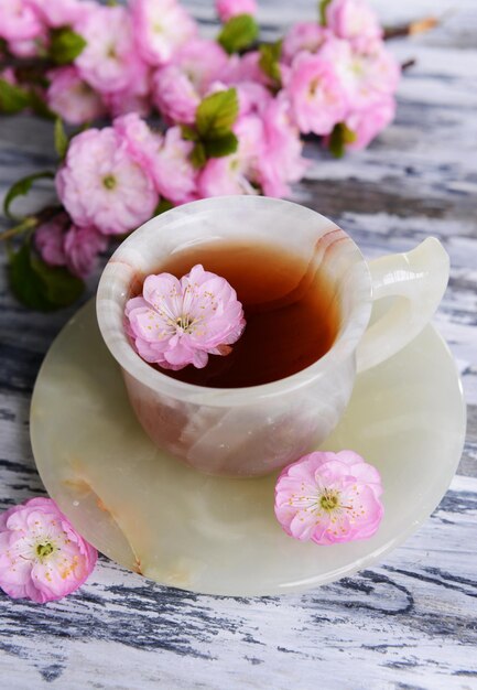 Hermosa flor de fruta con una taza de té en el primer plano de la mesa