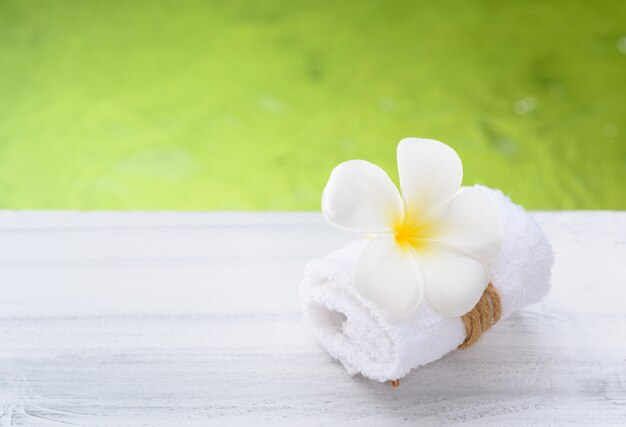 Hermosa flor de spa Frangipani con una toalla blanca en la mesa de madera con fondo de naturaleza verde piscina