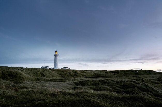 Hermosa foto de un faro en un campo bajo el cielo nublado