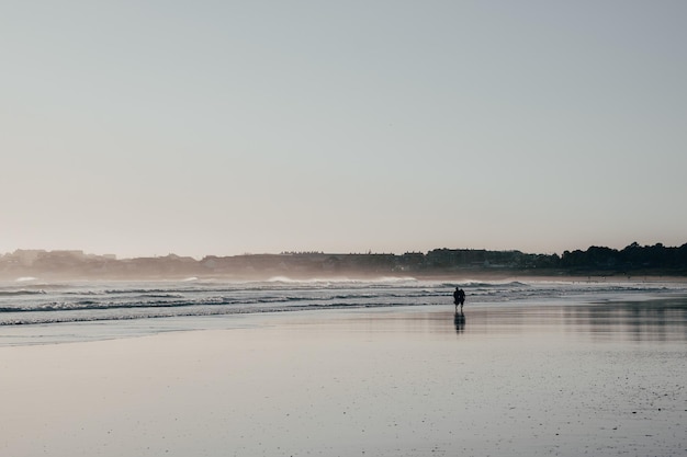 Hermosa foto de gente caminando en una playa en un día soleado de verano en Galicia, España