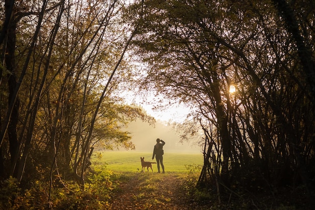 Hermosa foto de una mujer con su perro de pie en un prado