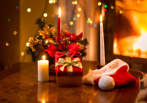 Hermosa foto de navidad de velas encendidas con caja de regalo contra la chimenea