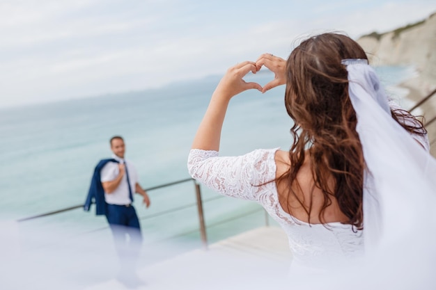 Hermosa foto de un puente haciendo formas de corazón con sus manos y ve al novio