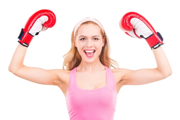 hermosa ganadora. Hermosa mujer de cabello rubio en ropa deportiva rosa y guantes de boxeo gesticulando