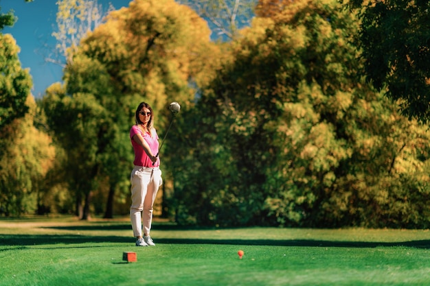 Hermosa golfista preparándose en el tee de salida