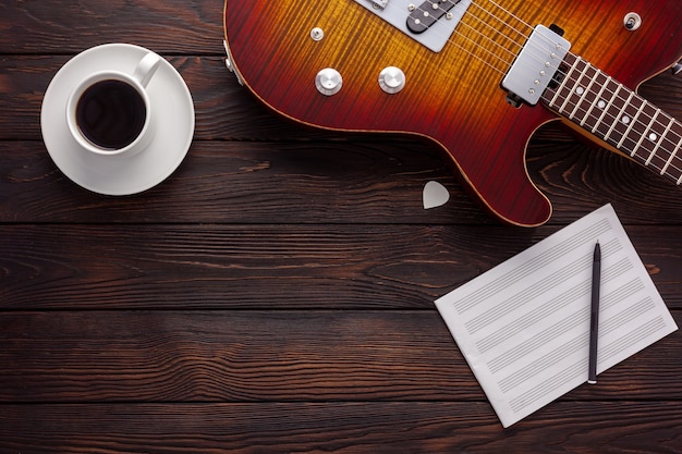 Hermosa guitarra eléctrica con auriculares y escritorio de café