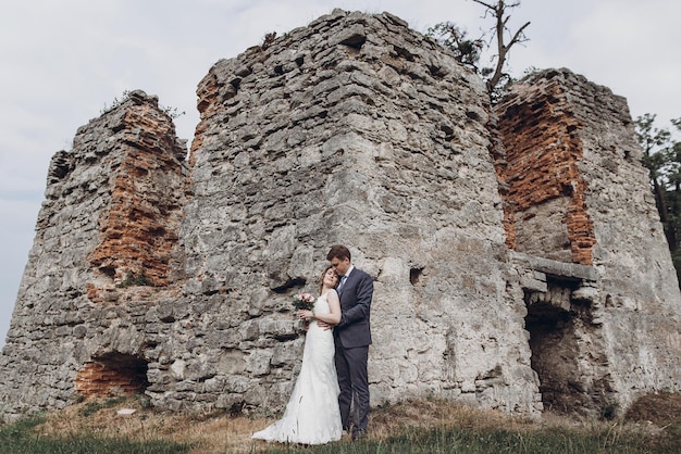 Hermosa hermosa novia y el novio besándose feliz pareja de novios abrazándose y abrazándose en el viejo castillo felices momentos románticos concepto de fuga espacio de amor sensual para texto