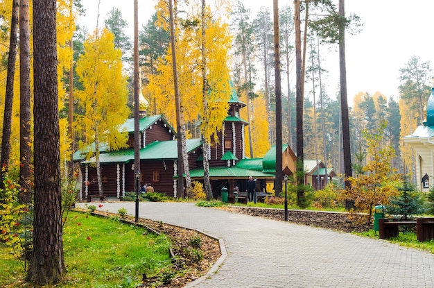 Hermosa iglesia de madera en medio de un bosque de otoño con un puente de madera