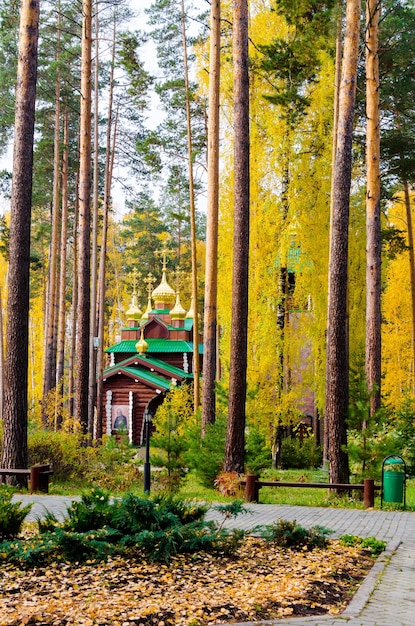 Hermosa iglesia de madera en medio de un bosque de otoño con un puente de madera