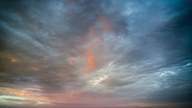 Hermosa imagen de nubes azules, naranjas, amarillas y rosadas en el cielo a la luz del sol al atardecer