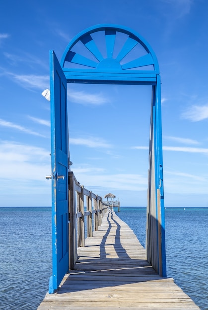 Hermosa imagen vertical de una puerta azul en el puente de madera durante el día en la isla de Roatán