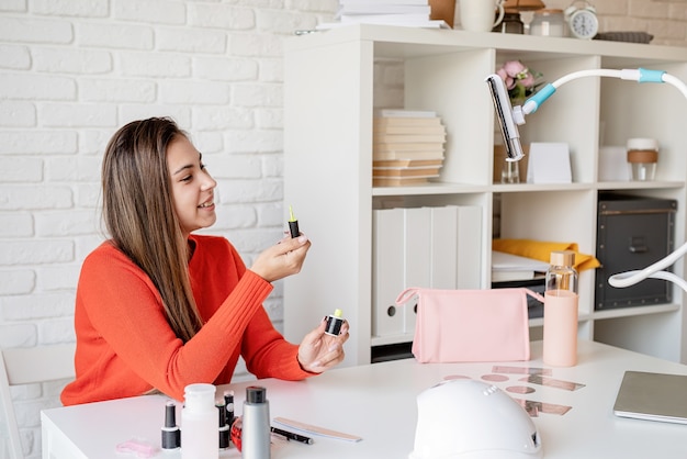 Hermosa influenciadora maestra de uñas caucásicas con video chat o haciendo un blog