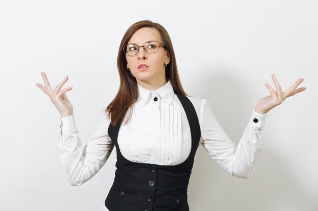 Hermosa inteligente pensativa caucásica reflexiva joven mujer de negocios de cabello castaño en traje negro, camisa blanca y gafas aisladas en la pared blanca