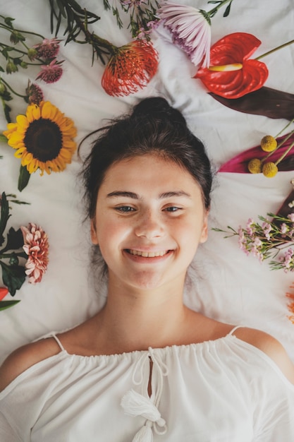 Hermosa joven acostada en una cama con flores