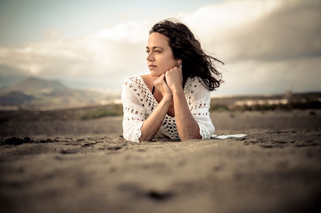 Hermosa joven se acostó en la playa disfrutando del viento, el clima y la libertad