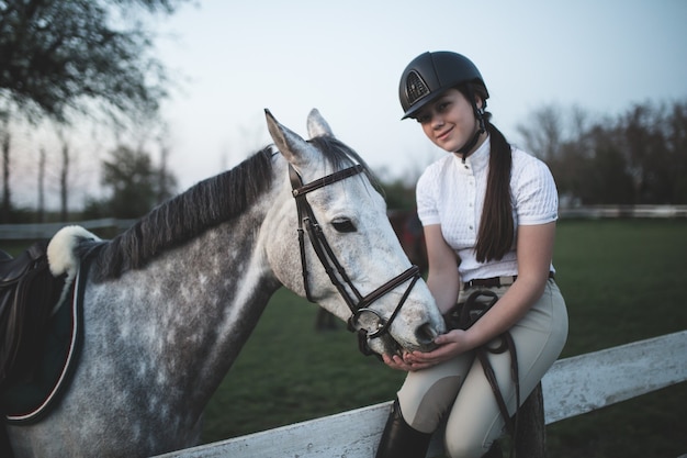 Hermosa joven adolescente disfrutando con su caballo en el rancho. Enfoque selectivo en caballo.