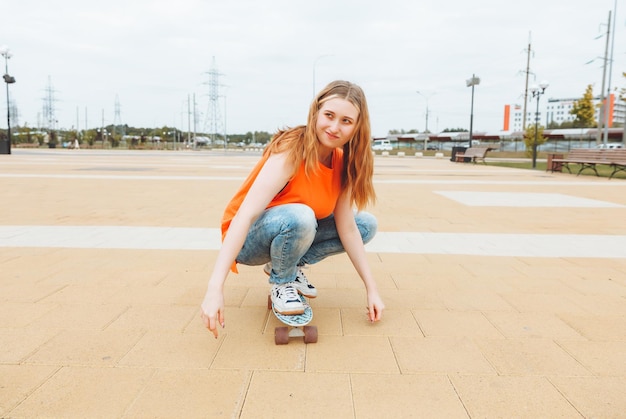 Una hermosa joven adolescente monta una patineta en el clima soleado generación z