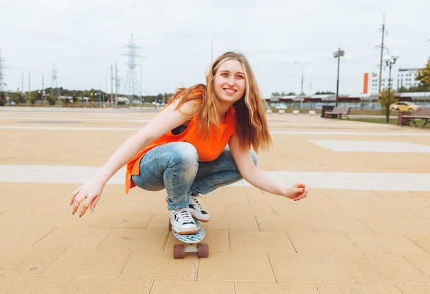 Una hermosa joven adolescente monta una patineta en el clima soleado generación z