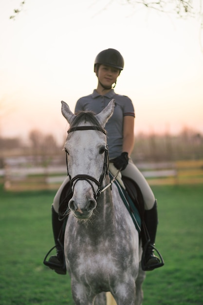 Hermosa joven adolescente montando su caballo en el rancho.