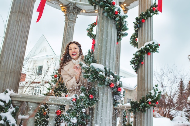 Hermosa joven adulta alegre y feliz en una hermosa glorieta en adornos navideños