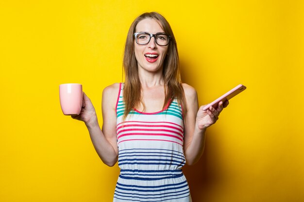 Hermosa joven afable con un teléfono y una taza de café