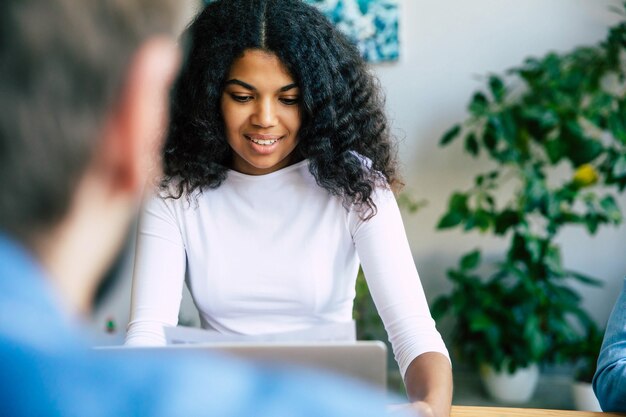 Hermosa joven africana en la oficina. El moderno equipo de puesta en marcha feliz con ropa informal en la oficina o en el espacio de trabajo conjunto está trabajando y discutiendo sus planes e ideas