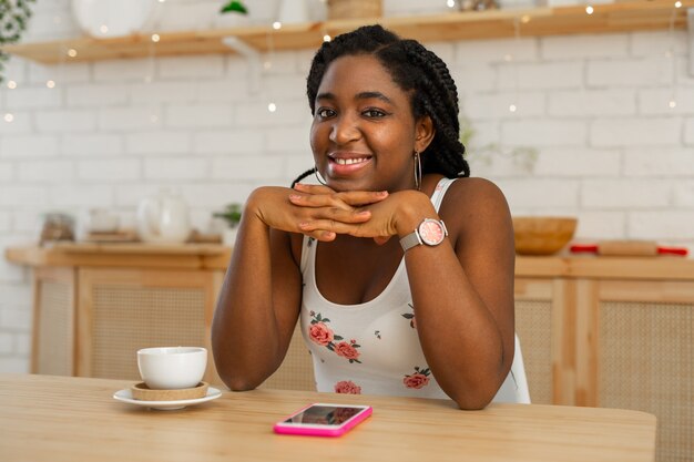 Hermosa joven africana sentada a la mesa en la cocina