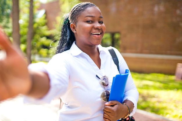 Hermosa joven africana sonriente con camiseta blanca y sosteniendo un cuaderno