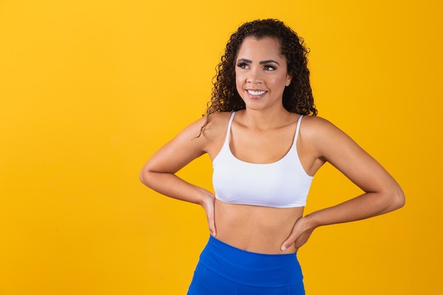 Hermosa joven afro en traje de fitness sonriendo mirando a cámara con espacio para texto. Horizontal