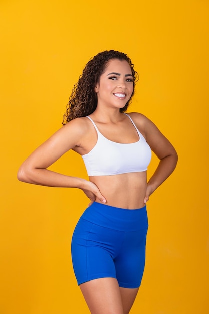 Hermosa joven afro en traje de fitness sonriendo mirando a cámara con espacio para texto. Vertical