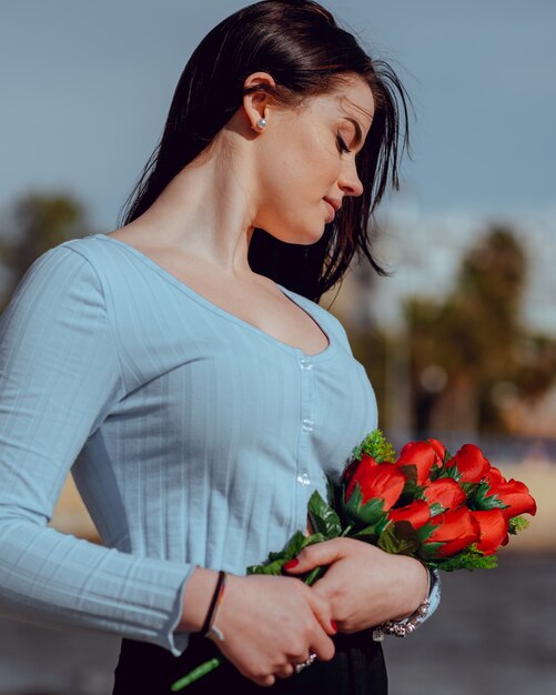 hermosa joven alegre y feliz mira un ramo de rosas al aire libre. Día de San Valentín