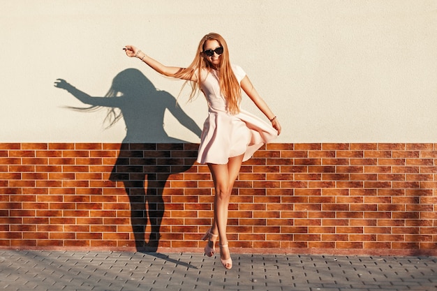 Foto hermosa joven alegre con una sonrisa saltando cerca de la pared. que te diviertas