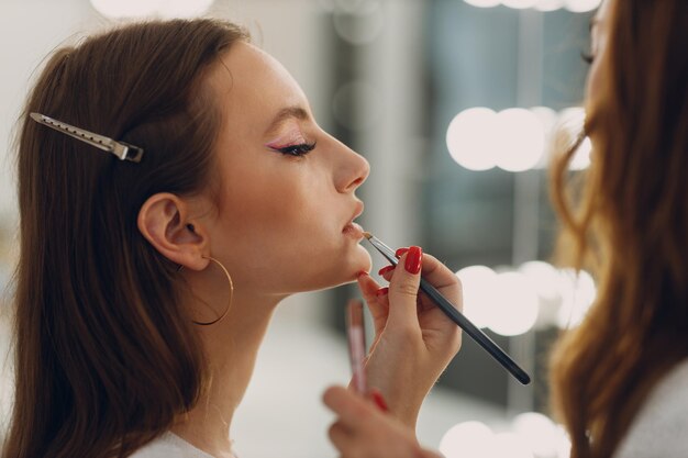 Hermosa joven aplicando pincel de rostro de belleza de maquillaje