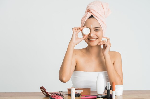 Foto hermosa joven asiática aplicando crema cosmética en su cara