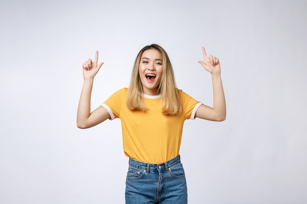 Foto hermosa joven asiática apuntando su dedo hacia arriba con expresión alegre