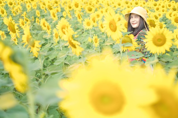 Hermosa joven asiática en un campo de girasoles en un colorido vestido casual