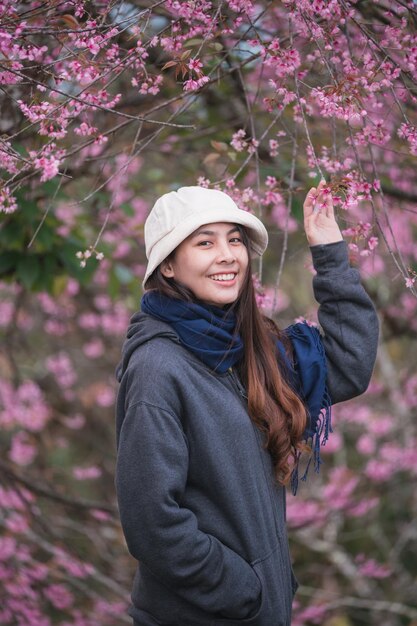 Hermosa joven asiática con cereza salvaje del Himalaya floreciendo en el jardín en primavera