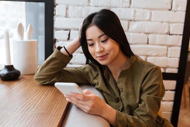 Hermosa joven asiática chateando por teléfono