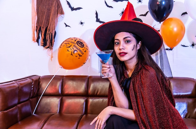 Hermosa joven asiática disfrazada de bruja divirtiéndose con un cóctel solo en la fiesta de Halloween por celebración, Pretty Woman sonriendo y disfrutando en casa.