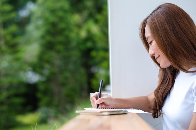 Una hermosa joven asiática escribiendo en un cuaderno al aire libre