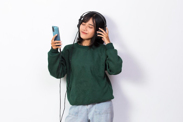 Hermosa joven asiática escuchando música y danza aislada de fondo blanco